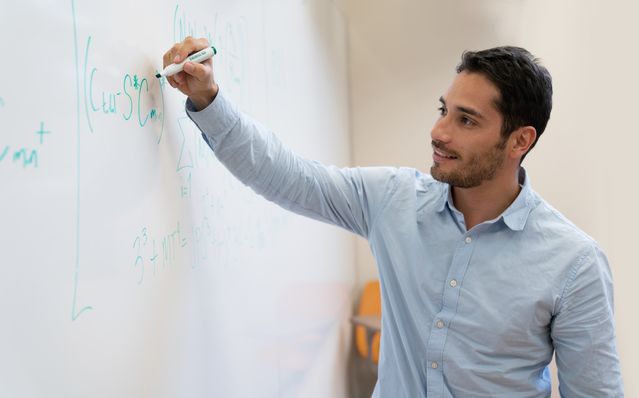 Ung mann skriver matematiske formler på en tavle
