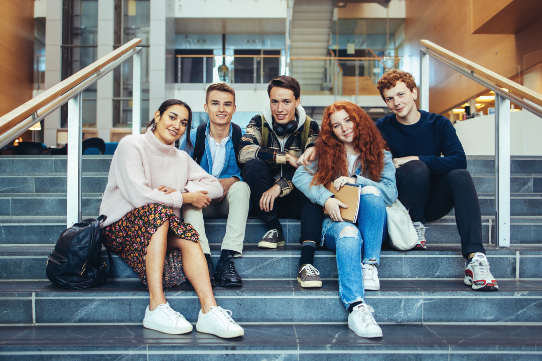 smilende studenter sittende i en trapp