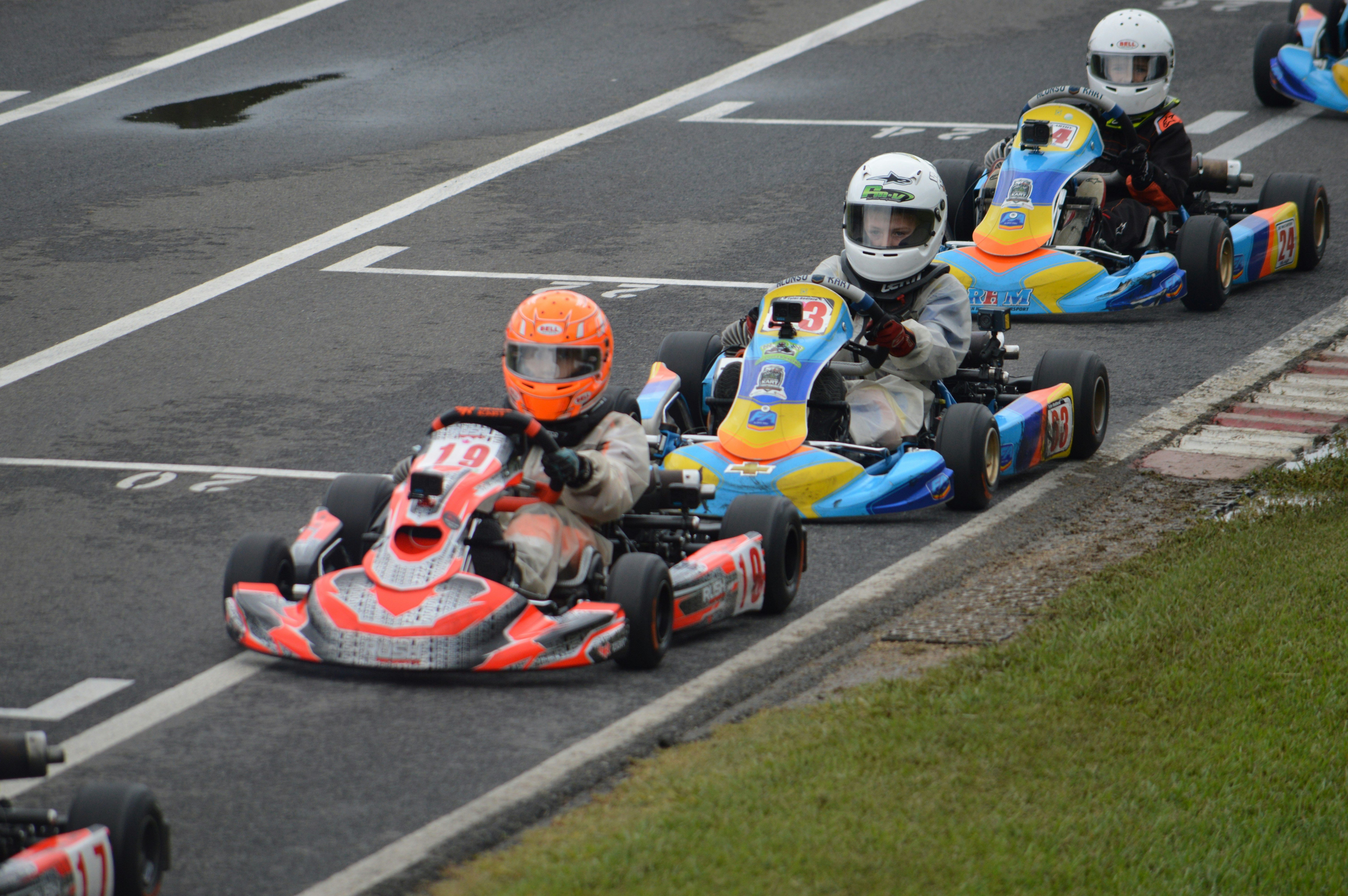 Fotografi av tre personer som sitter i gokarter i rekke. 
