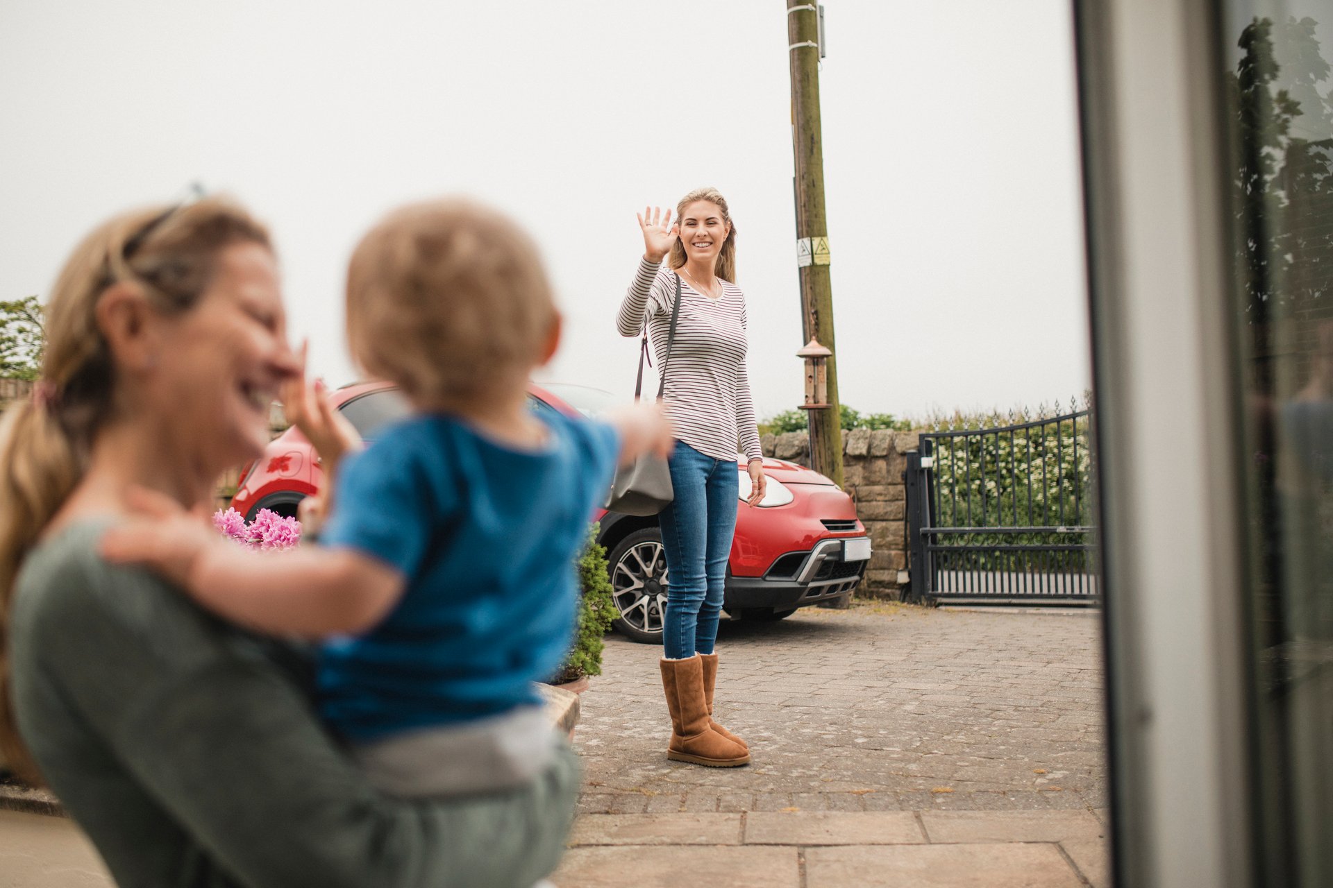 En kvinne vinker farvel til en baby som sitter i fanget til en eldre kvinne. Illustrerer barnepass når du skal på kurs.