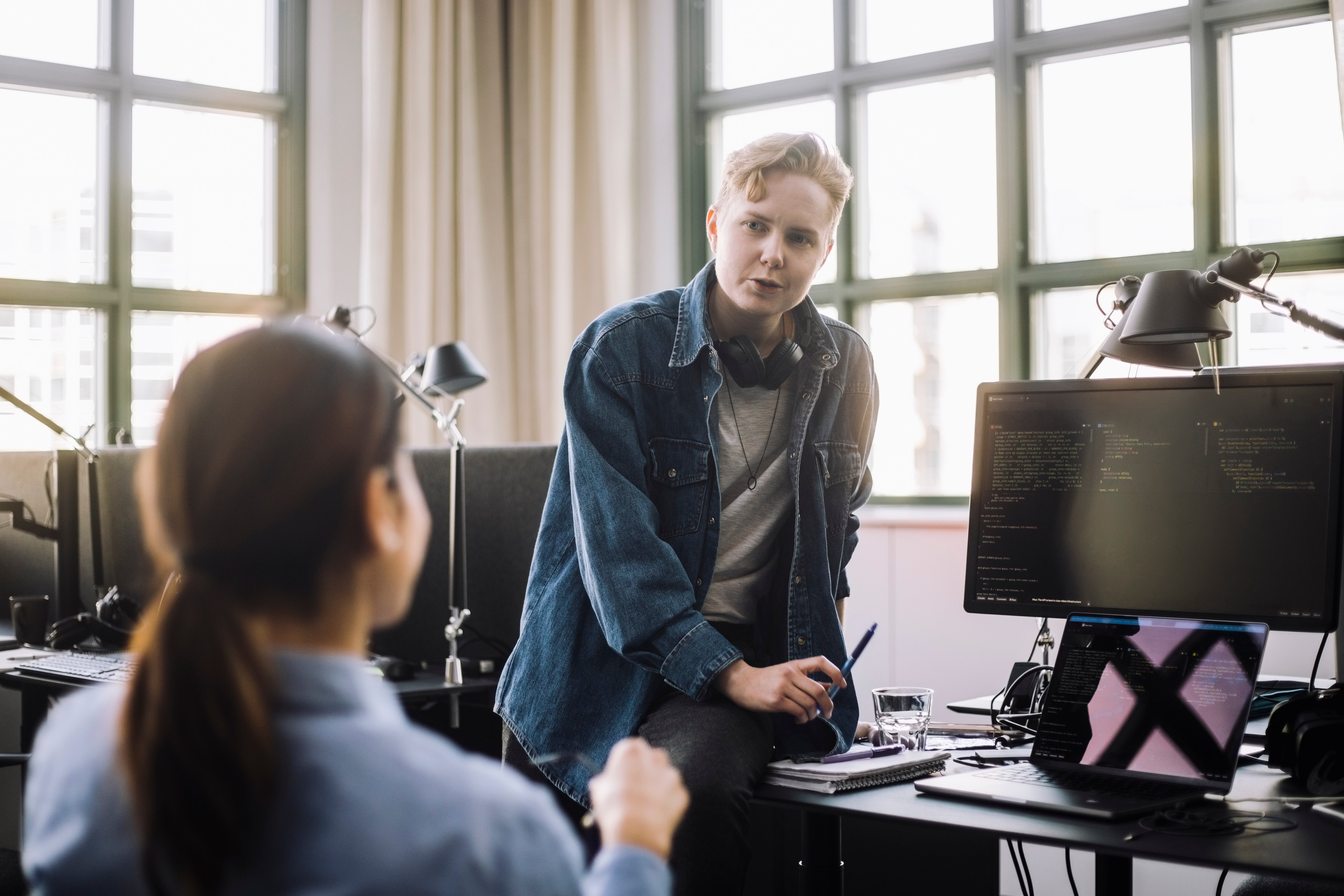 To kontorarbeidere har en samtale i et moderne kontorlandskap. Illustrerer dialog om midlertidig ansettelse og arbeidsrettigheter.