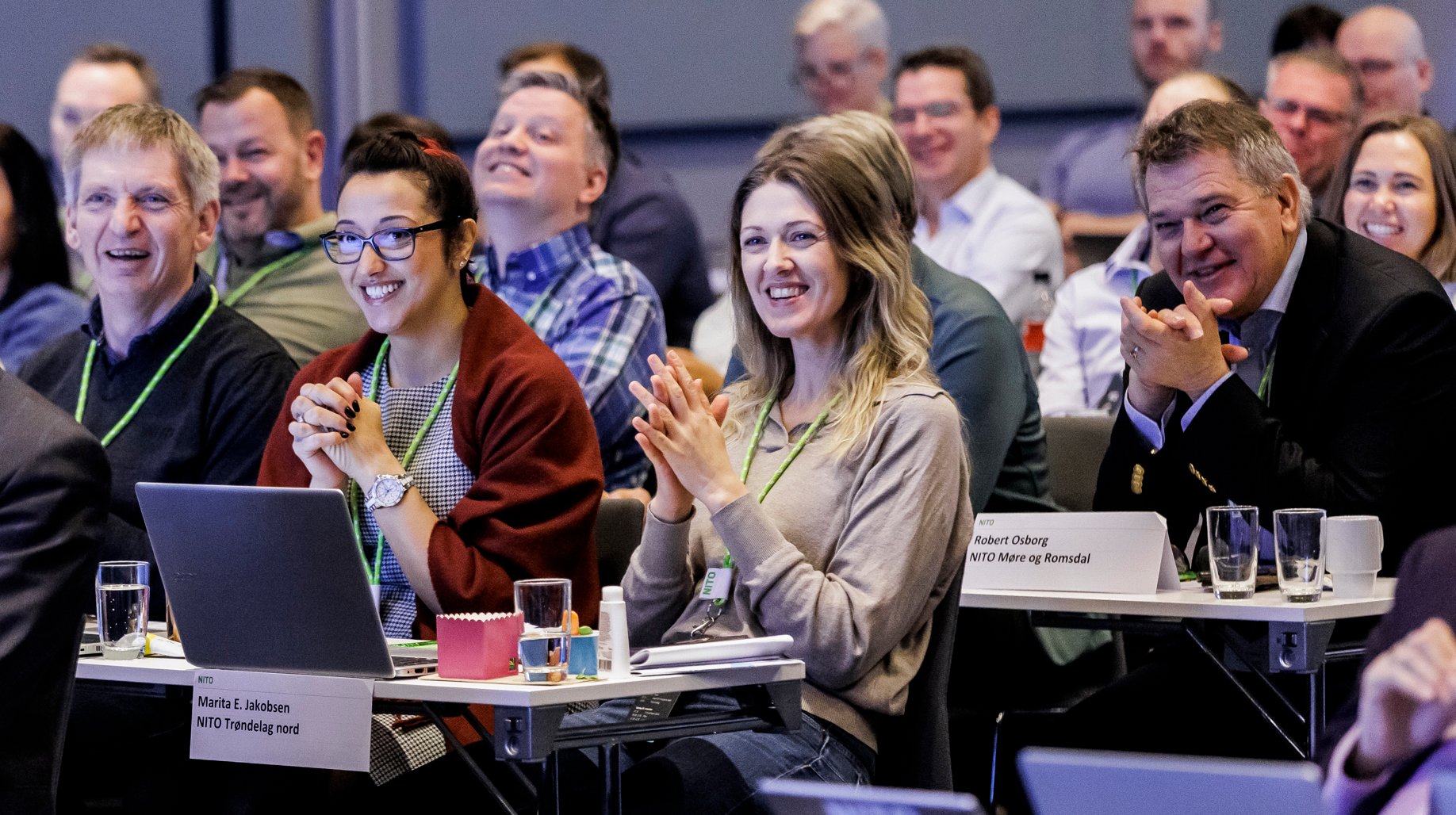 Engasjerte tillitsvalgte fra NITO applauderer på en sentral tariffkonferanse, klare for årets lønnsoppgjør.