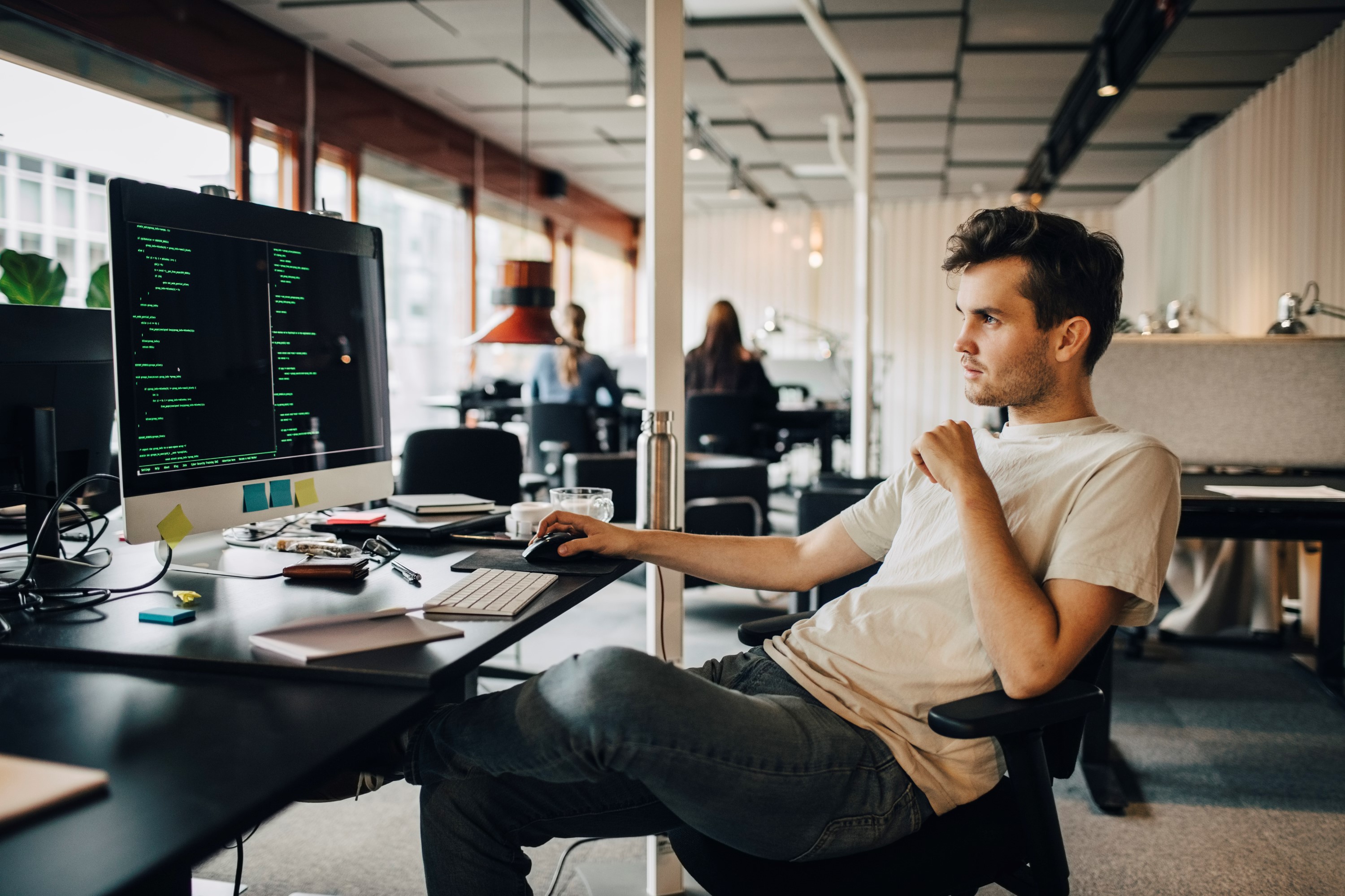 A male employee works concentrated at a computer in a modern office. He represents those with particularly independent positions.