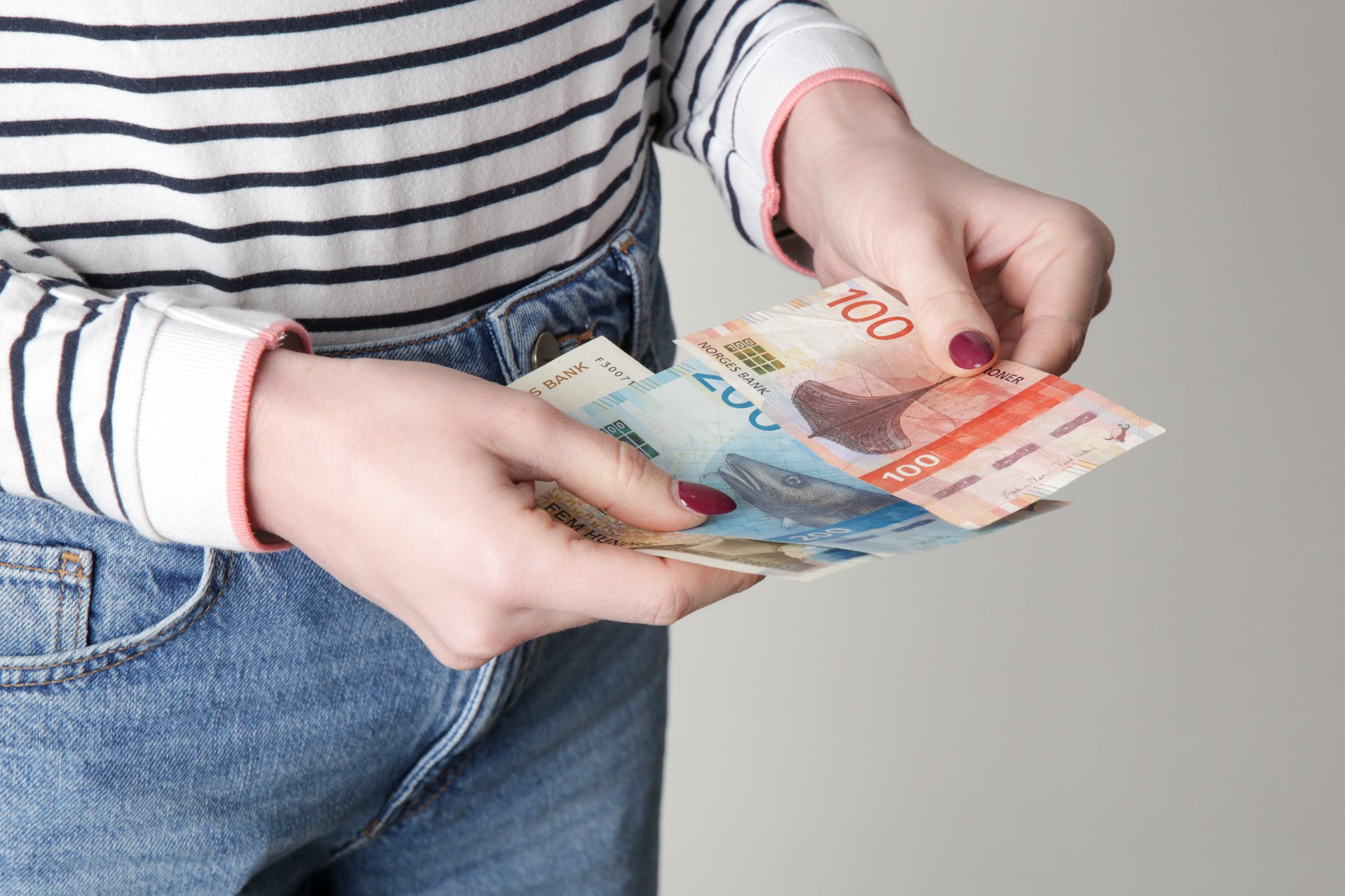 En person teller norske pengesedler, som symboliserer lønn og resultatet av lønnsoppgjøret.