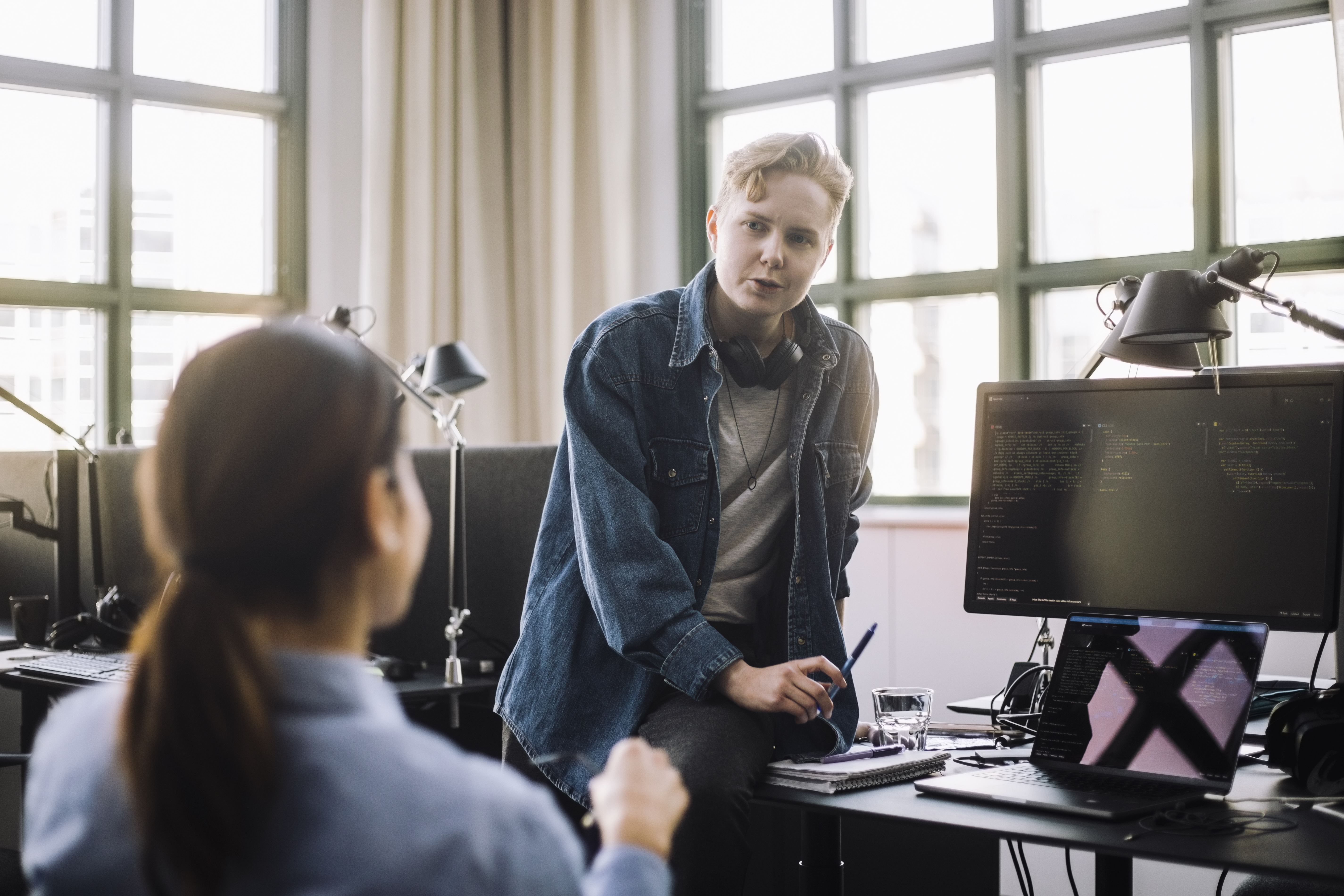 To kontorarbeidere har en samtale i et moderne kontorlandskap. Illustrerer dialog om midlertidig ansettelse og arbeidsrettigheter.