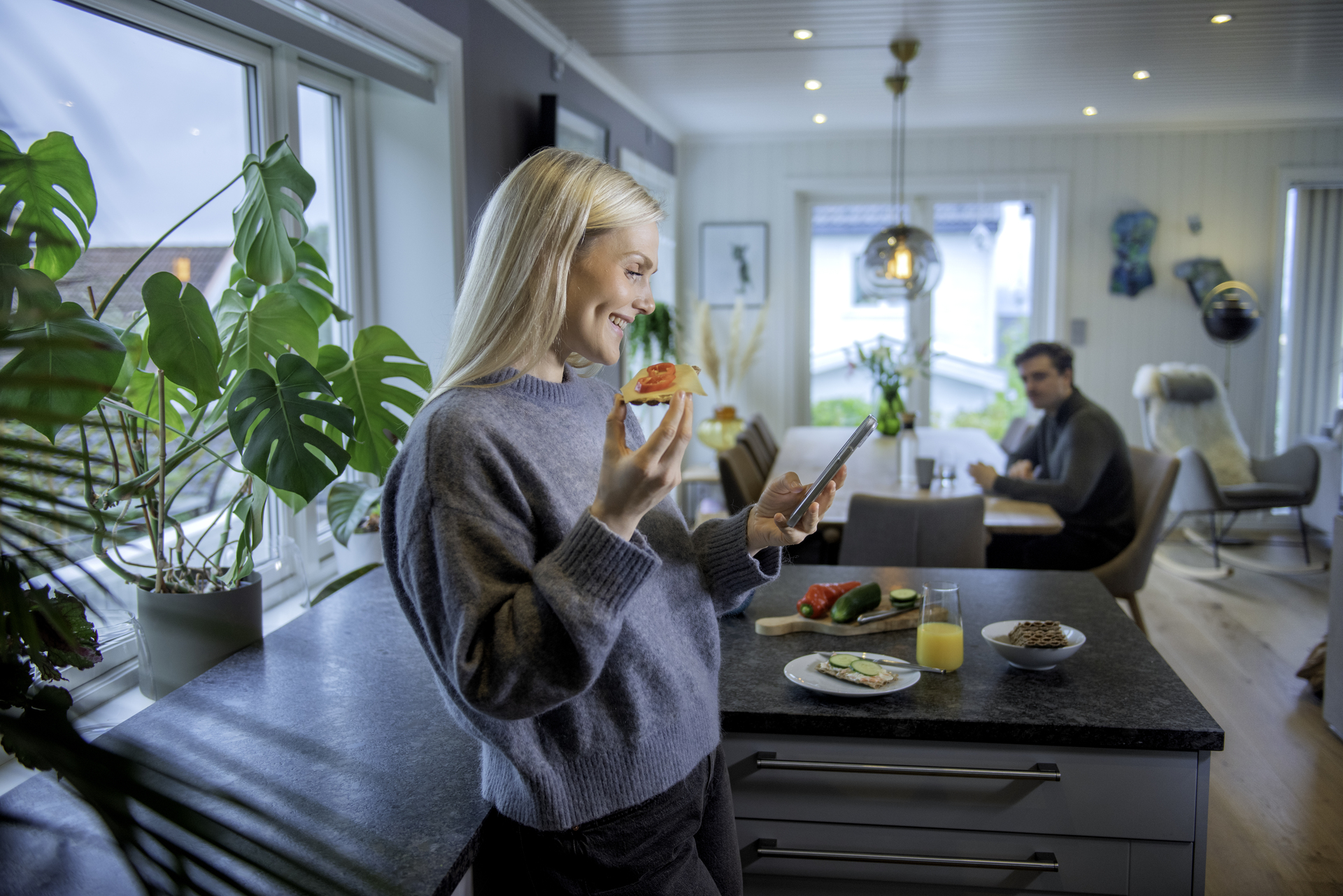 Ung dame er hjemme og ser på telefon mens hun spiser