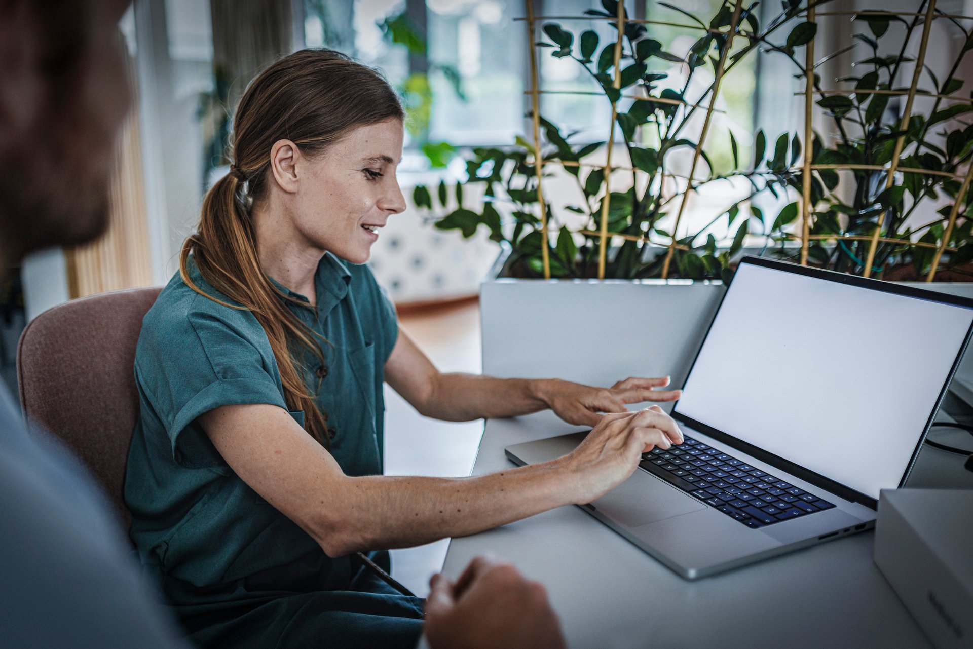Kvinne i grønn topp som sitter og jobber på en pc