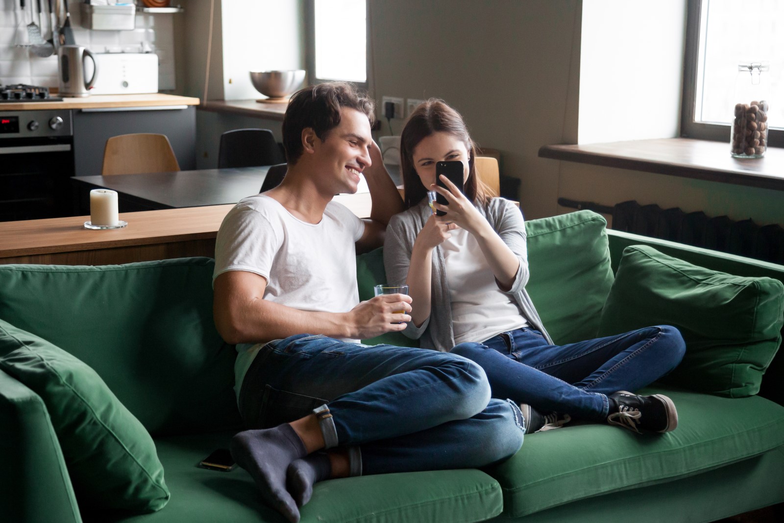 To personer i en sofa som ser på mobiltelefon. Foto:Shutterstock