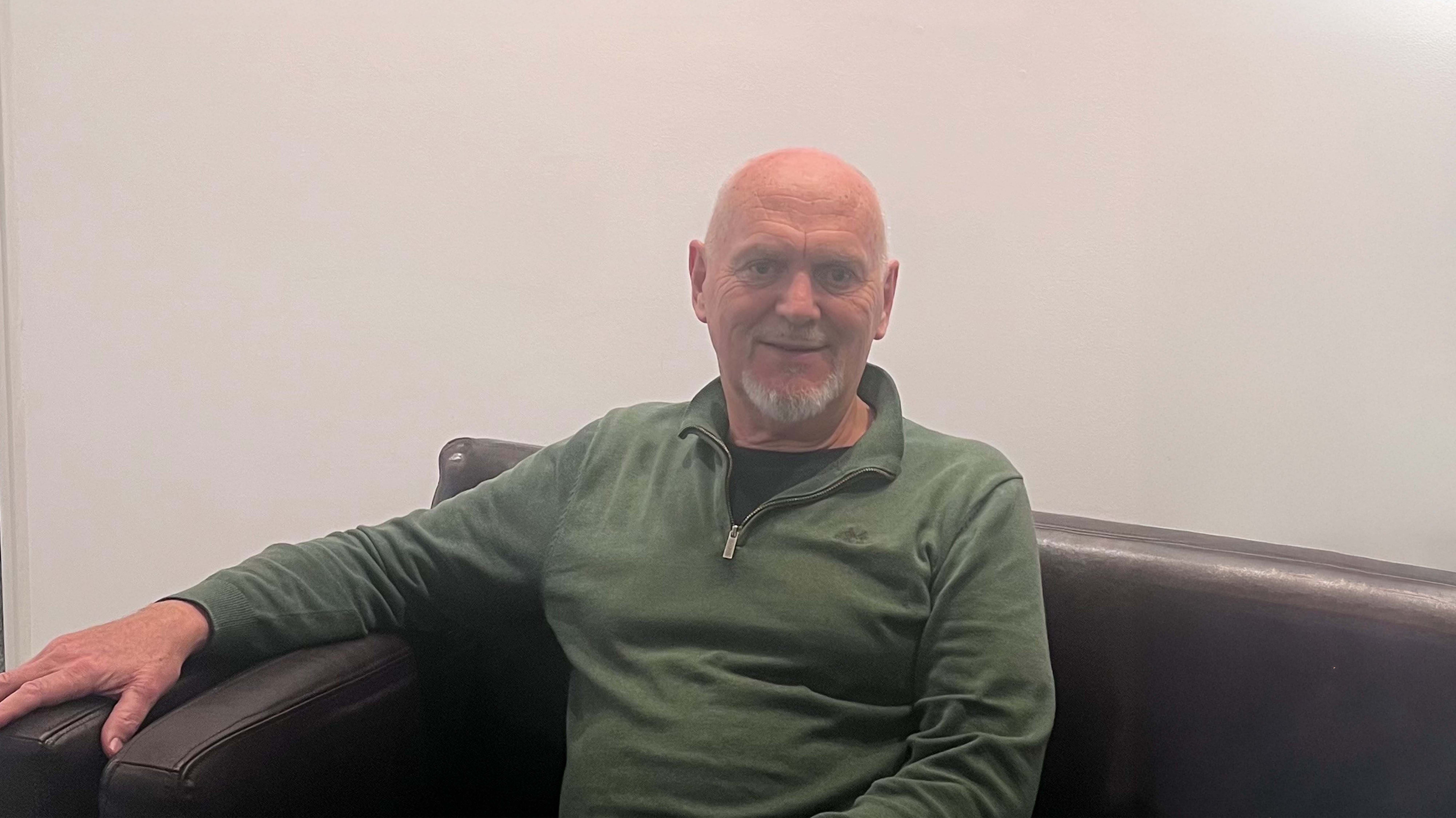 Man sitting on a sofa - smiling while looking into the camera