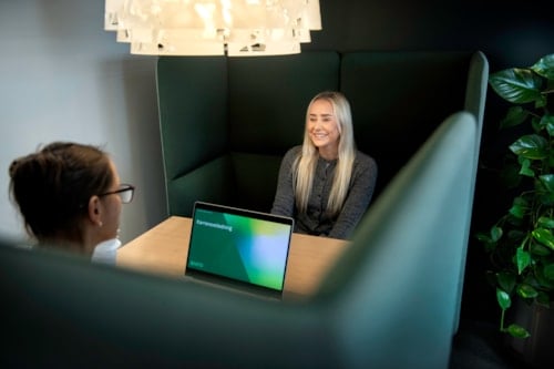 To damer sitter på hver sin side av bordet og prater