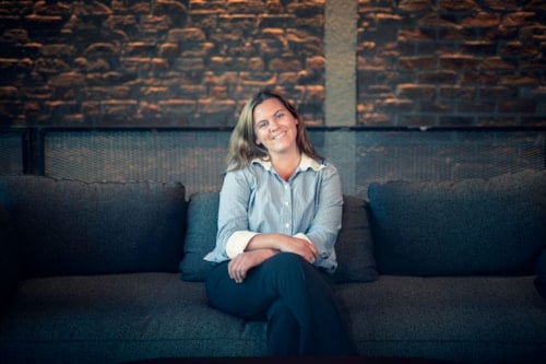 Ung smilende dame som sitter på en sofa