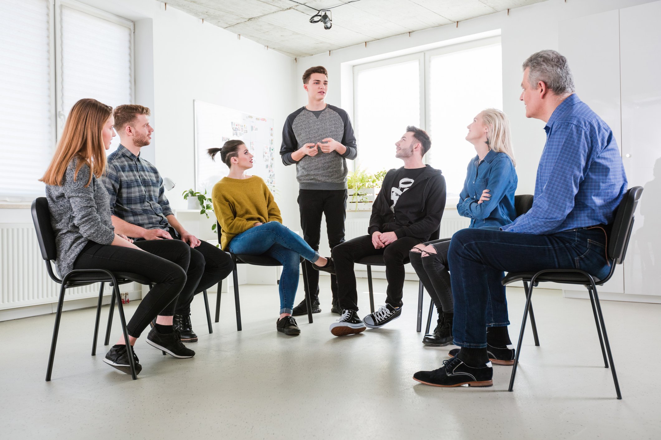 Personer som sitter på stoler i en hestesko.